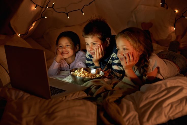 Niños viendo una película en una tienda de campaña